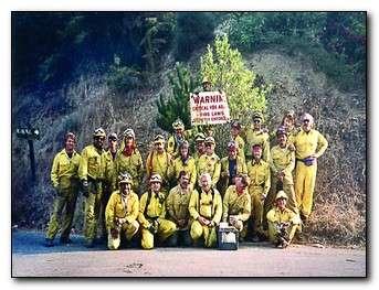 group of firefighters standing in front of warning sign
