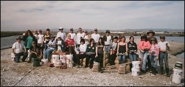 group of people sitting/standing in front of bay with buckets and shovels 