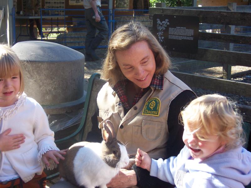 Volunteer Docent with rabbit and two smiling children