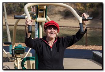 Person with a red hat using park fitness equipment