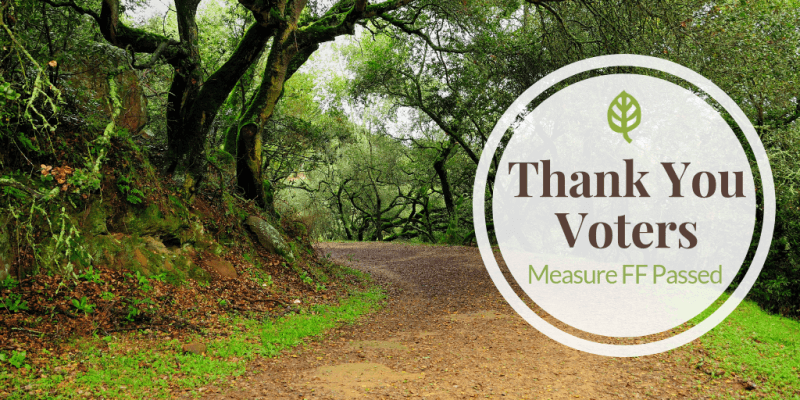 Trail with trees and white circle with text saying thank you voters measure FF
