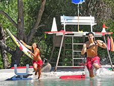 Lifeguards doing a drill, running into a pool with boards in hand