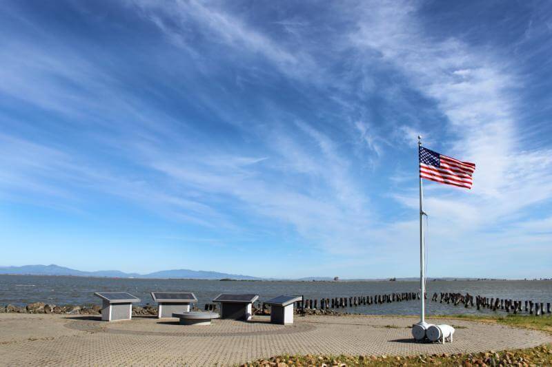 American flag flying beside memorial with SF Bay in the background